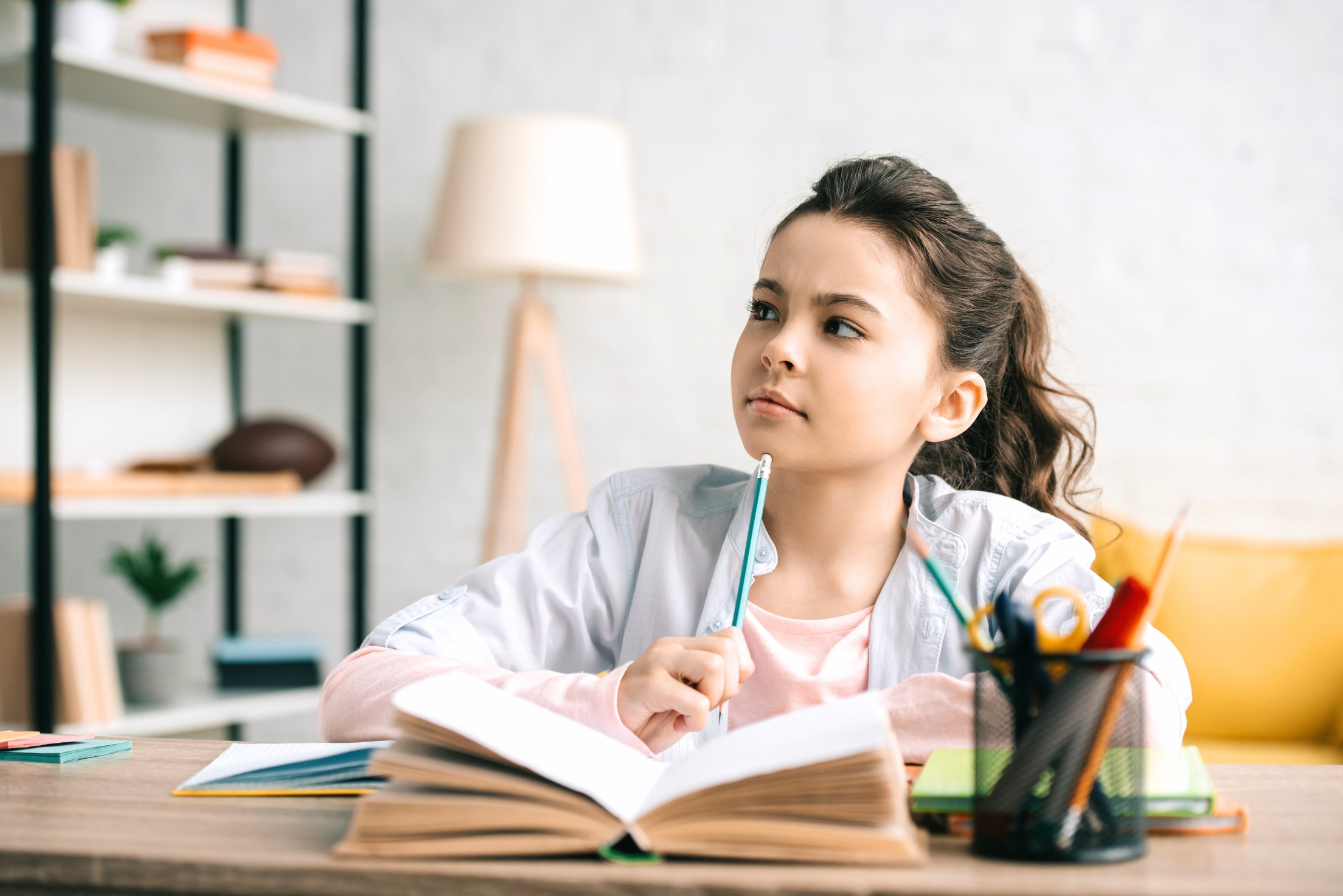 Kid Journal: Elementary school girl considering her writing prompts for her daily journal entry. 